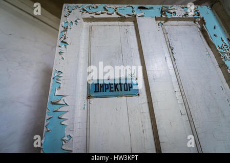 Door of headmaster office in secondary school in Mashevo abandoned village of Chernobyl Nuclear Power Plant Zone of Alienation in Ukraine Stock Photo