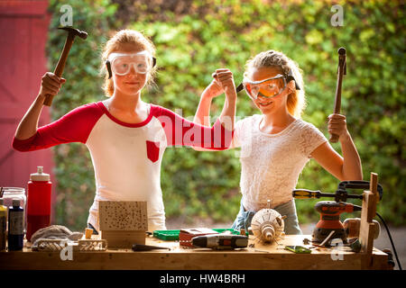 Sisters flexing muscles and holding hammers Stock Photo