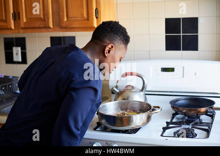 Black woman smelling food cooking in pan on stove Stock Photo