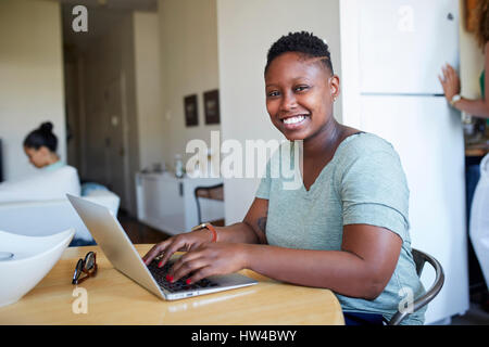 Smiling Black woman using laptop at table Stock Photo