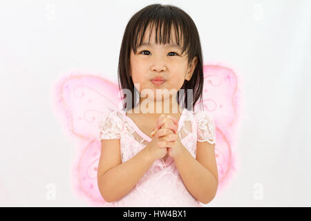 Chinese little girl wearing butterfly custome with praying gesture in plain white background Stock Photo