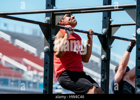 Hispanic man doing chin-ups outdoors Stock Photo