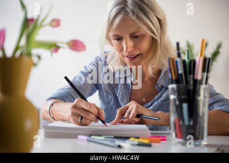 Caucasian woman sketching on pile of paper Stock Photo