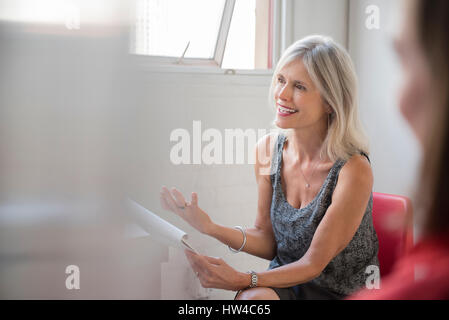 Gesturing Caucasian businesswoman with notepad talking in meeting Stock Photo
