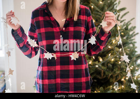 Caucasian woman holding Christmas ornaments on string Stock Photo