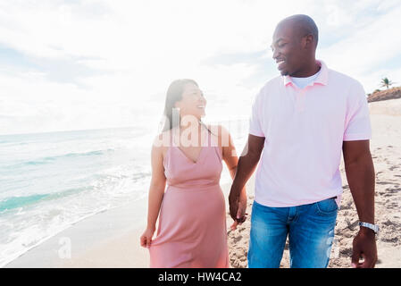 Couple holding hands walking on beach Stock Photo