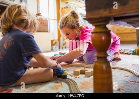 Caucasian brother and sister playing with toy race track on floor Stock Photo