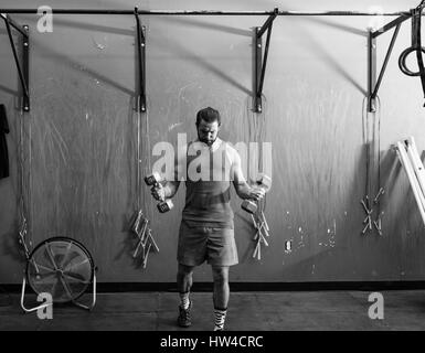 Mixed Race man lifting dumbbells in gymnasium Stock Photo