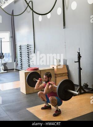 Mixed Race man lifting barbell in gymnasium Stock Photo