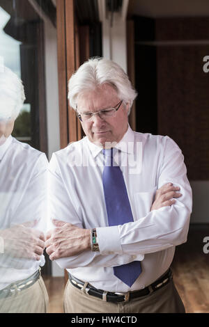 Pensive Caucasian businessman leaning on window Stock Photo