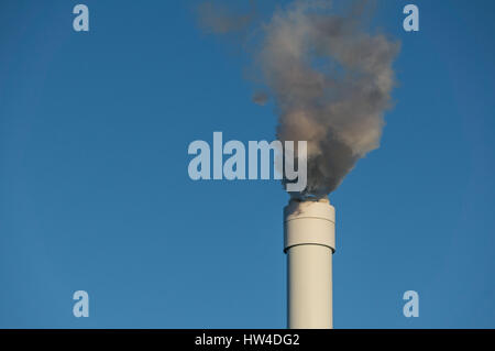 Smoke coming from a chimney, rising against a clear nice blue sky Stock Photo