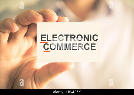 Closeup on businessman holding card with EC ELECTRONIC COMMERCE acronym text, business concept image with soft focus background and vintage tone Stock Photo
