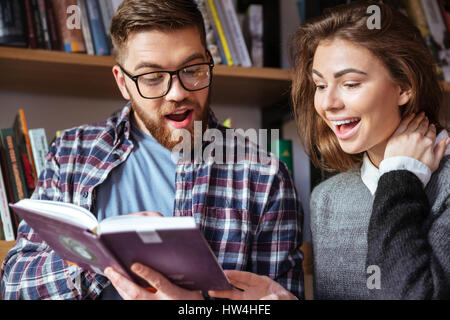 Couple of students reading book in a library together Stock Photo