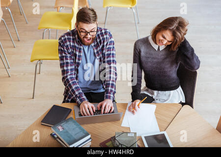 Top view of a group of students working on a project together while sitting at the library desk Stock Photo