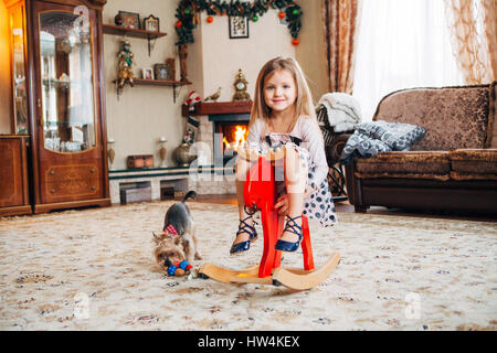 girl on a toy horse at home Stock Photo