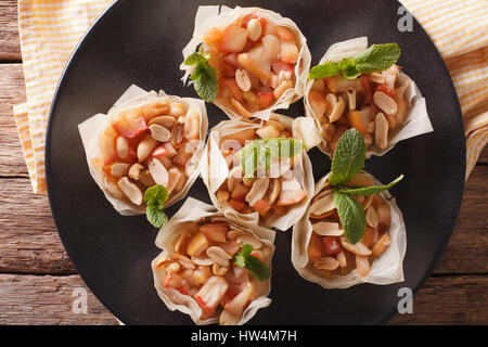 Cups of dough filo stuffed with apples and peanuts close-up on a plate. Horizontal view from above Stock Photo