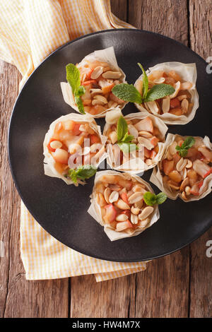 Homemade Mini Phyllo Cups with apples and peanuts closeup on a plate. Vertical view from above Stock Photo