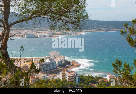 View from the hills in St Antoni de Portmany & surrounding area in Ibiza.  Hotels along the beach, places to stay.  Waves crash as surf onto shore. Stock Photo