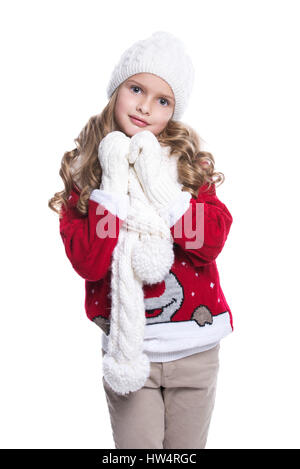 Cute smiling little girl with curly hairstyle wearing knitted sweater, scarf, hat and gloves isolated on white background. Winter clothes Stock Photo