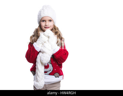 Cute smiling little girl with curly hairstyle wearing knitted sweater, scarf, hat and gloves isolated on white background. Winter clothes Stock Photo