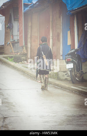 Sapa, Vietnam - May 6, 2014: Hmong man in traditional clothes walking down the street in the heavy fog in Sapa village, Vietnam. Stock Photo