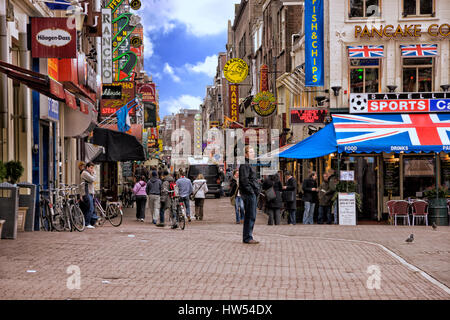 People standing and walking in a cobbled street in Amsterdam, Netherlands Stock Photo