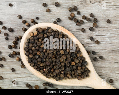 Black Pepper Corns on a Spoon Against a Grey Background Stock Photo