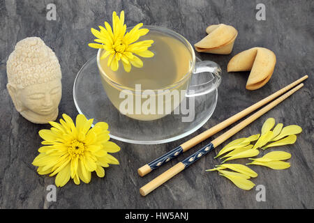 Chrysanthemum herb flower tea with glass cup,fortune cookies, chopsticks and stone buddha head. Also used in traditional chinese and japanese herbal m Stock Photo