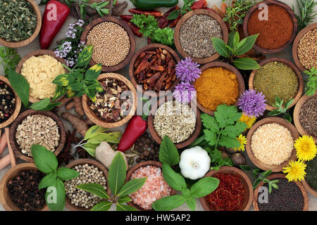 Herb and spice sampler in wooden bowls and loose forming a background, high in vitamins and antioxidants. Stock Photo