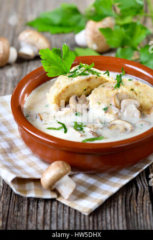 Mushroom sauce with bread dumplings served in a ceramic bowl on a wooden table Stock Photo