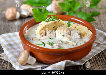Mushroom sauce with bread dumplings served in a ceramic bowl on a wooden table Stock Photo