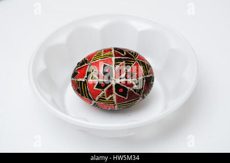 An Easter egg is decorated with traditional Ukrainian folk ornament using a wax-resist method. The pysanka is covered with wax and dyed red and yellow Stock Photo