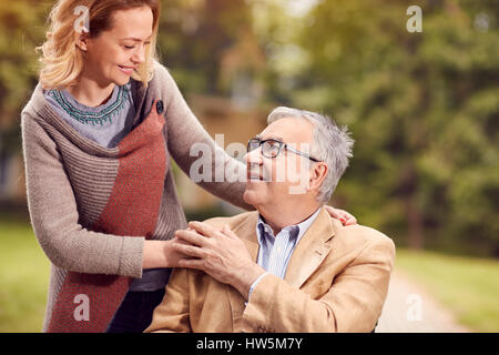 daughter enjoying with her senior smiling father in wheelchair Stock Photo