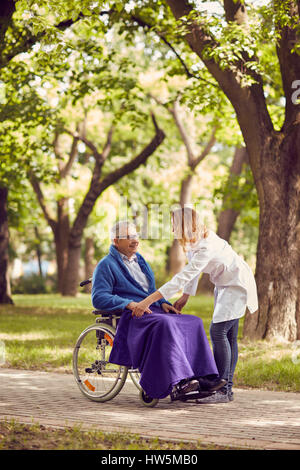 Male nurse helping senior man in wheelchair in the park Stock Photo