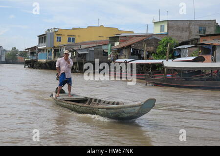 A shanty town at riverside of dirty river Mekong in Vietnam. Wooden cottages are set on a wooden pillars, fixed into muddy river bed. Stock Photo