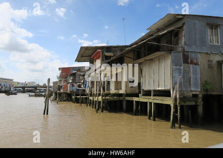 A shanty town at riverside of dirty river Mekong in Vietnam. Wooden cottages are set on a wooden pillars, fixed into muddy river bed. Stock Photo