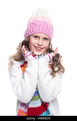 Smiling cute little girl wearing knitted sweater and colorful scarf, hat, mittens isolated on white background. Winter clothes Stock Photo