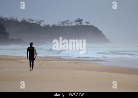 Lone surfer on beach in Australia on stormy day with big surfer Stock Photo
