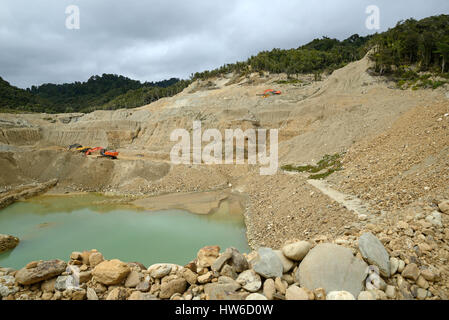 A digger clears overburden at an open cast mine to reach the gold-bearing paydirt below. Stock Photo