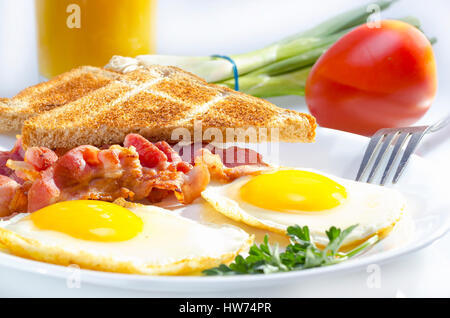 Bacon with sunny side up eggs served with toasts. Stock Photo