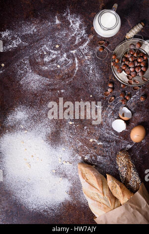 Dough preparation. Baking ingredients: egg, flour, milk, nuts on a rustic table. Freshly baked bread baguette. Flat lay, copy space. Stock Photo