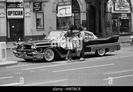 Music fans admire a vintage U.S. car during the Rock and Roll Radio Campaign march through Central London, England on May 15, 1976. The campaign aimed to get more vintage rock and roll music played on BBC radio. Stock Photo