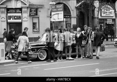 Music fans admire a vintage U.S. car during the Rock and Roll Radio Campaign march through Central London, England on May 15, 1976. The campaign aimed to get more vintage rock and roll music played on BBC radio. Stock Photo