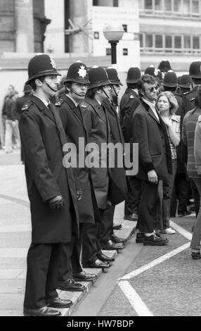 A music fan in Teddy Boy fashion stands with a line of police officers during the Rock and Roll Radio Campaign march in Central London, England on May 15, 1976. The campaign aimed to get more fifties style rock and roll music played on BBC radio. Stock Photo