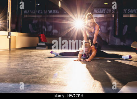Young athletic woman doing stretching pilates exercises with exercise trainer Stock Photo