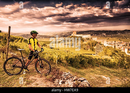 Cyclist admires from the hill the Soave castle views. Stock Photo