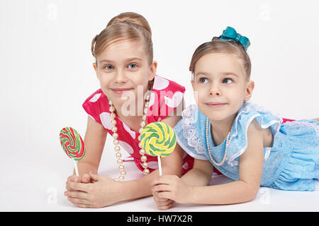 Two sisters lie nearby and hold in his hand a beautiful large candy Stock Photo