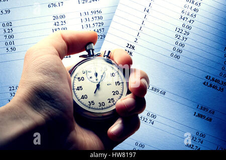 Hand holding stopwatch on budget numbers in closeup Stock Photo