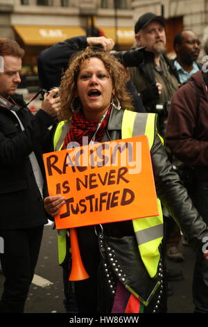London, UK, 18th March 2017. Campaign group Stand Up to Racism holds a march through central London to mark UN anti-racism day. One of the stewards holds up a sign that says: 'Racism is never justified'. Roland Ravenhill/ Alamy Live News Stock Photo