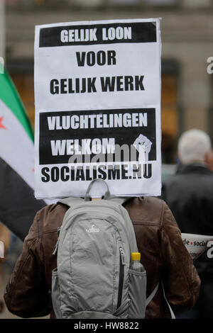 Amsterdam, Netherlands. 18th Mar, 2017. An activist holds a sign that reads 'Equal pay for equal work - refugees welcome'. Around 2,000 people marched through Amsterdam, to protest against racism and discrimination. The protest was part of an European wide day of protest against the EU Turkey Refugee Deal and the International Day for the Elimination of Racial Discrimination (21. March). Photo: Cronos/Michael Debets Credit: Cronos Foto/Alamy Live News Stock Photo